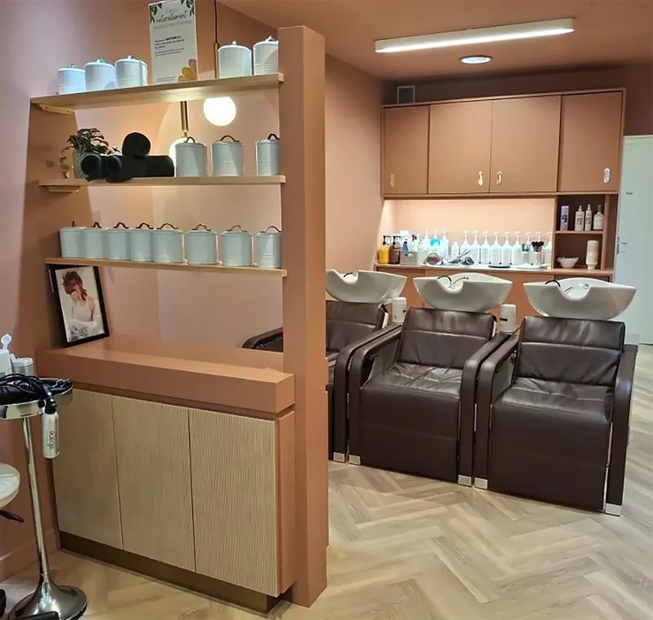 Salon de coiffure moderne avec trois bacs de lavage équipés de fauteuils en cuir marron et vasques blanches ergonomiques