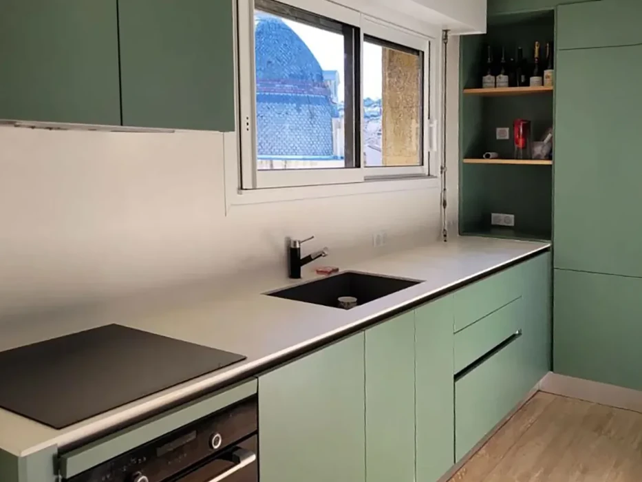 Cuisine moderne avec façades vert sauge, plan de travail blanc, évier noir encastré et robinetterie contemporaine