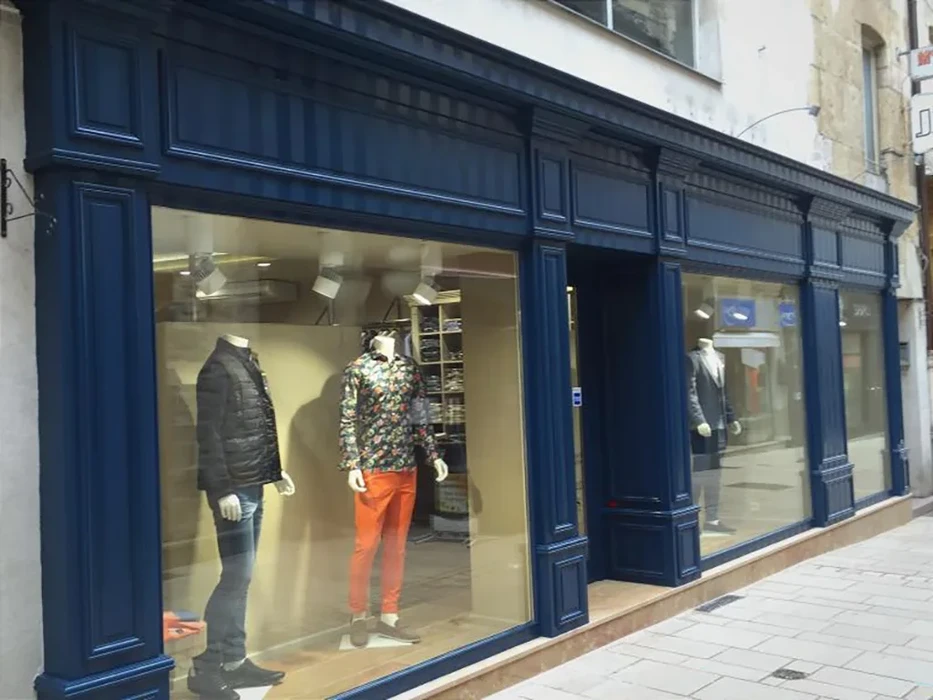 Devanture de magasin de vêtements masculins avec façade en bois peint bleu marine et grandes vitrines