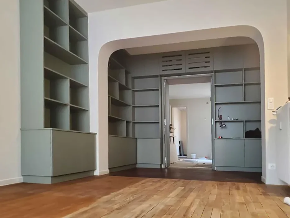 Intérieur moderne avec bibliothèque sur mesure vert sauge, arche architecturale donnant sur une seconde pièce avec rangements intégrés